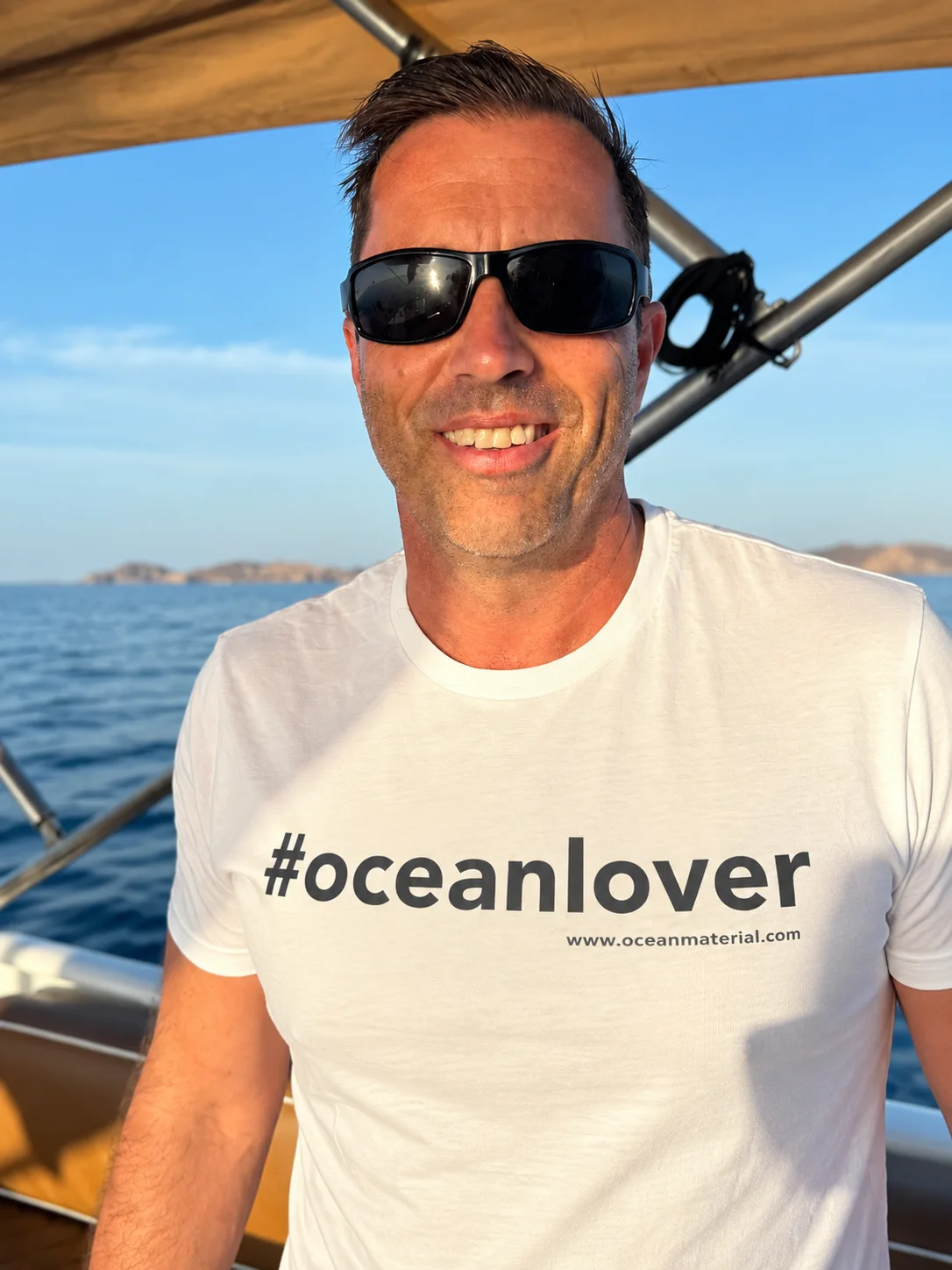 Christian Redl on a boat at sea, wearing a white #oceanlover T-shirt